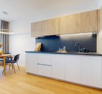 A kitchen with a dining table, four chairs, light wooden cabinets, and appliances in a 2-room apartment.