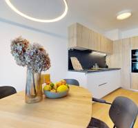 A kitchen with light wooden furniture, flowers, and fruit on the table in a 2-room apartment.