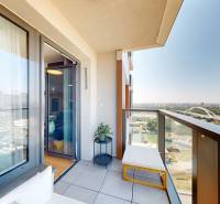 A balcony with seating, a view of the Danube and surrounding buildings from a 2-room apartment.