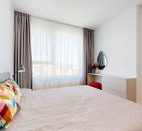 A bright bedroom in a two-room apartment with colorful pillows and a dressing table.