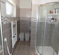 Shower enclosure and radiator in the bathroom of a family house with gray tiles.