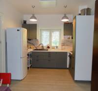 A kitchen in a family house with a white refrigerator, gray cabinets, and a window above the sink.