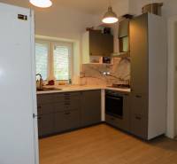 A kitchen in a family house with a gas stove, a white refrigerator, and a window with a view.