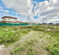 A residential plot in Senec at Južná Brána with a grassy area and fencing.