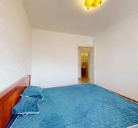 A bright bedroom with a patterned wall and a bed in a 4-room apartment.