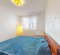 A bright bedroom with a blue bed and decorative wallpaper in a 4-room apartment.