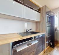 A kitchen in a 4-room apartment with a wooden countertop, sink, and built-in appliances.