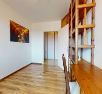 Room with wooden flooring, shelves, a table, and decoration in a 4-room apartment.