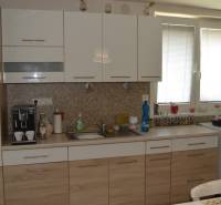 A kitchen in a family house with white and wooden cabinets and kitchen appliances.