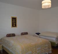 A bedroom in a family house with an ornate yellow bedspread and a ceiling light.