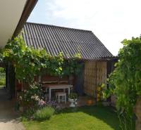 A family house in Trstín with a terrace, a garden table, and lush vegetation.