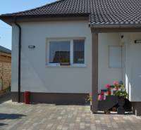 A family house in Trstín with a flat roof and a paved courtyard, decorated with flowers.