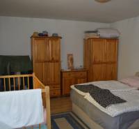A bedroom in a family house with a wooden bed, cabinets, and a baby crib.
