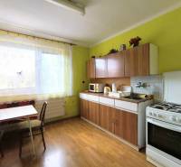 A kitchen in a family house with a window, a counter, and a stove, green walls.