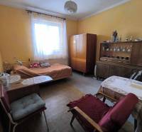 A room in a family house with a bed, antique furniture, and a table with a chair.
