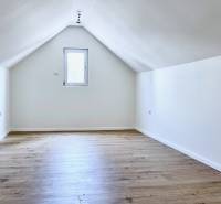 Attic room in a cottage with wooden floor and white walls.