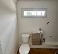 A toilet with a sink in the interior of a cabin and a wooden floor.