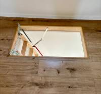 A ladder leading under the wooden floor in a cabin, with modern wooden paneling.