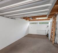 A spacious garage with white walls in a villa, a wooden ladder, and windows.