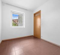 An empty room with brown tiles and a large window in a villa.
