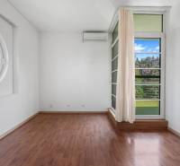 A bright room with a circular window, wooden floor, and a view of the garden in a villa.