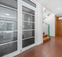 A hallway in the villa, a staircase with wooden steps, and glass doors.