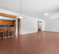 Spacious interior of a villa with a kitchen seating area, staircase, and lighting fixture.