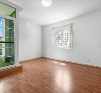 A room with a wooden floor, a round window, and access to a balcony in a villa.