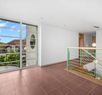 Interior of a villa with a staircase and large windows, offering a view of the surrounding architecture.