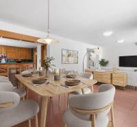 Dining table with a set table, comfortable chairs, kitchen with wooden cabinets in the background.