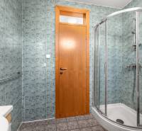 A bathroom in a villa with tiles, a shower cabin, and wooden doors.