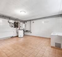 Technical room in the villa with a boiler and a sink, light tiles and cladding.