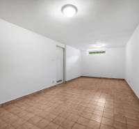 A spacious room with white walls and tiles resembling a basement floor of a villa.