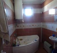 A bathroom in a family house with a bathtub, a sink, and tiling.
