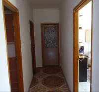 A hallway in a family house with wooden door frames and tiles.