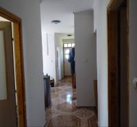 A corridor with tiles and white walls in a family house.