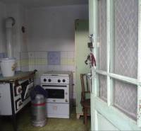 A kitchen in a family house with a stove, a gas cooker, and a bucket on the table.