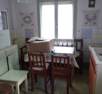 A kitchen in a family house with older furnishings and furniture, floral decorations on the wall.