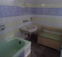A bathroom in a family house with a bathtub, a sink, and a bench.