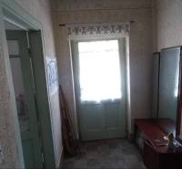A hallway in a family house with wooden doors, a mirror, and decorative embroideries.