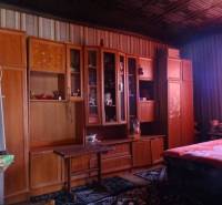 A room in a family house with a wooden wardrobe, a bed, and colorful curtains.