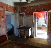 The interior of a family house with floral wallpaper and a traditional stove.