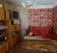A room in a family house with floral wallpaper, a bed, and an old television.