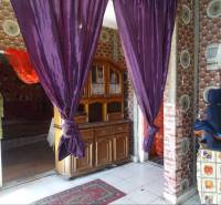 A family house with purple curtains, a wooden dresser, and patterned walls.