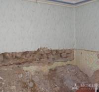 The interior of a family house with a wall in poor condition and damaged plaster cladding.