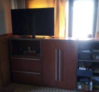 Living room in a family house with a cabinet, television, and curtains over the window.