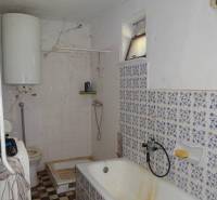 Bathroom with a bathtub and a boiler in a family house. The tiles and flooring have patterns.