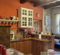 A kitchen in a family house with a wooden cabinet, a ceramic stove, and hanging shelves.