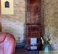 Interior of a family house with a tiled stove, a leather armchair, and stone walls.