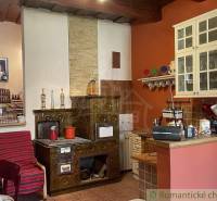 A kitchen in a family house with antique tiles, a wooden ceiling, and a shelf with dishes.